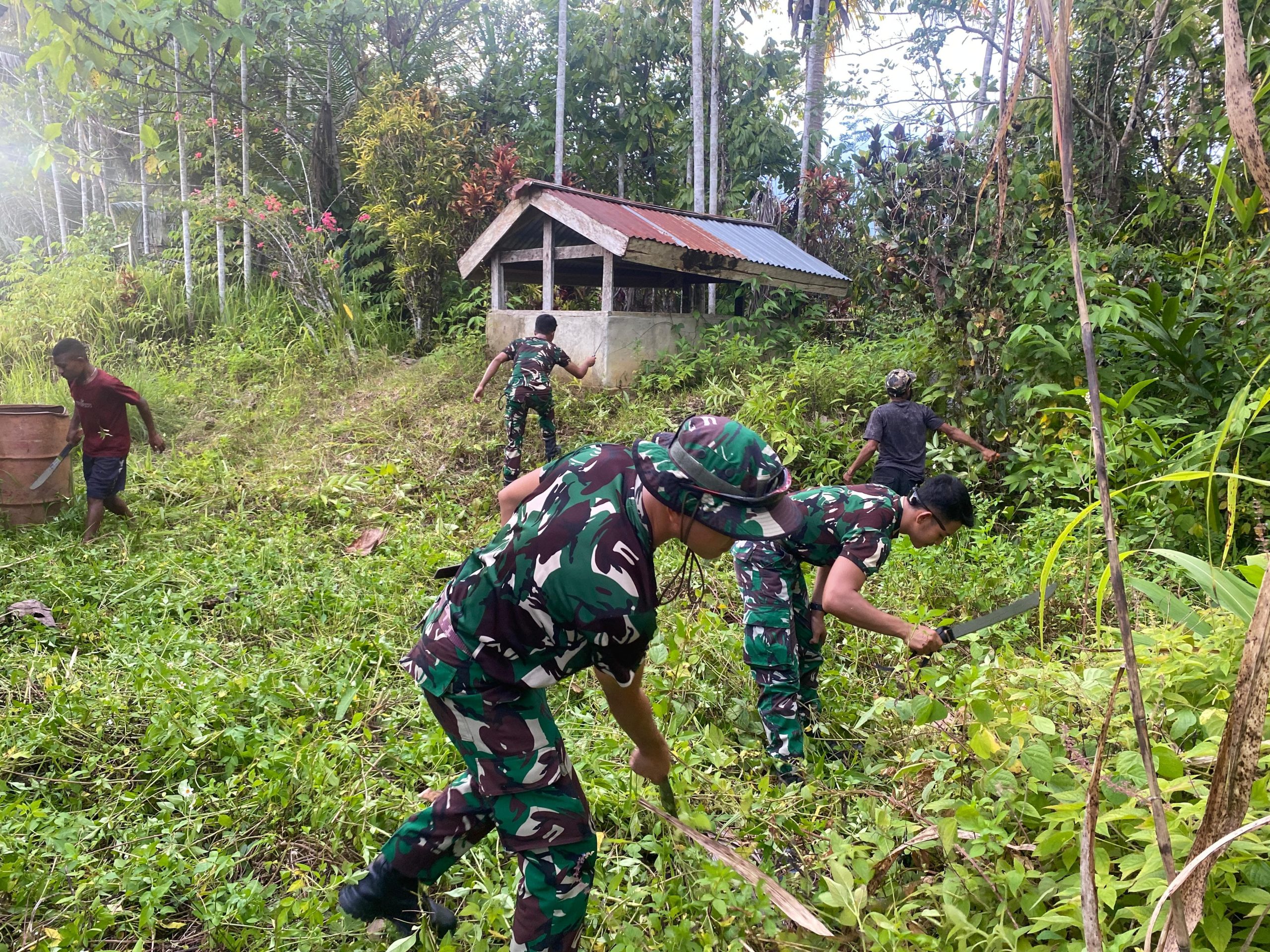 Bersih-bersih Lingkungan Makam, Satgas Yonif 512 QY Gelar Karya Bakti Bersama Masyarakat di Kampung Monggo Efi.